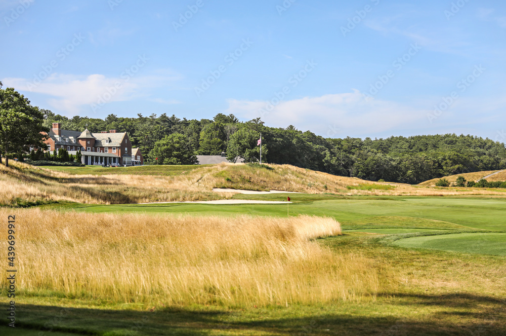The brick clubhouse on a rise above the course, with tall golden grass in the foreground